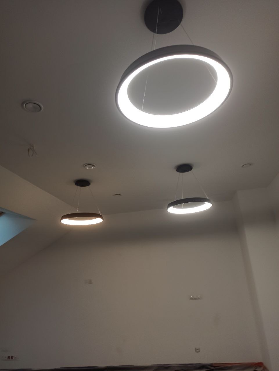 Nowoczesne, okrągłe lampy LED zamontowane na suficie w jasnym pomieszczeniu. Oświetlenie punktowe i główne. Minimalistyczny design.