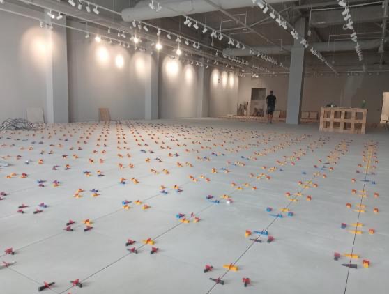 Przygotowanie podłoża pod układanie płytek w dużej przestrzeni. Rozstawione klipsy i kliny poziomujące płytki. Widoczna siatka linii wyznaczających ułożenie.