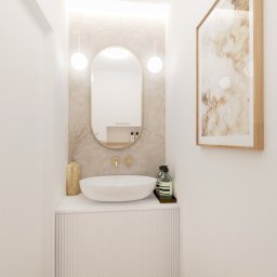 Zuzanna Rybicka Sikora Architekt Wnętrz - Minimalistyczna łazienka: owalne lustro z oświetleniem, umywalka nablatowa na szafce z ryflowanym frontem, beżowe płytki, złote akcenty i abstrakcyjny obraz w ramie.