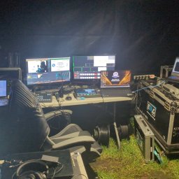 DELTA CRAFT SPÓŁKA Z OGRANICZONĄ ODPOWIEDZIALNOŚCIĄ - Stanowisko reżyserskie z kilkoma monitorami i laptopami podczas wydarzenia. Widoczne konsole sterujące, okablowanie i elementy nagłośnienia.