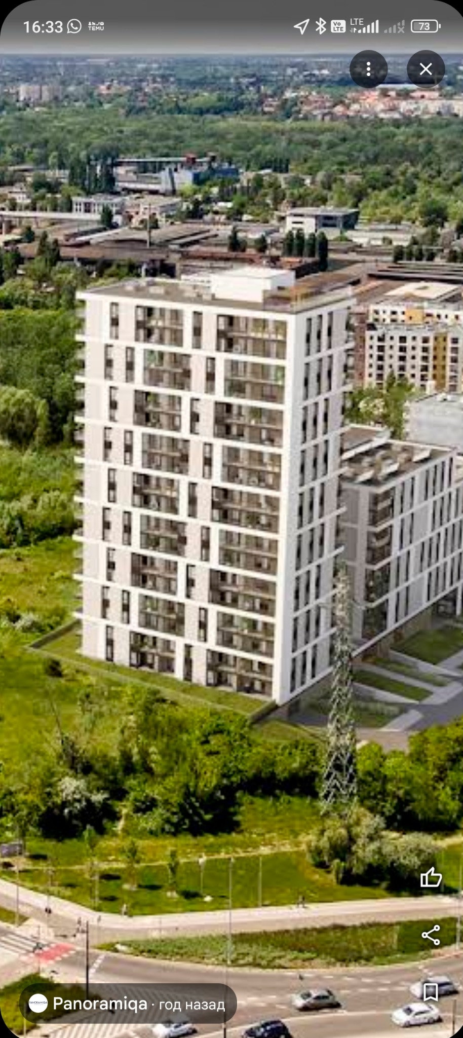 Biały, nowoczesny budynek mieszkalny z licznymi balkonami, otoczony zielenią i drogami. Ujęcie z góry, widoczne detale architektoniczne i otoczenie miejskie.