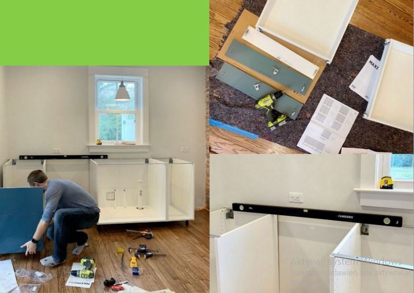 Instalacja szafek kuchennych: mężczyzna montuje niebieski front do białej szafki, poziomica, wkrętarka, instrukcja obok. Widok na okno i drewnianą podłogę.