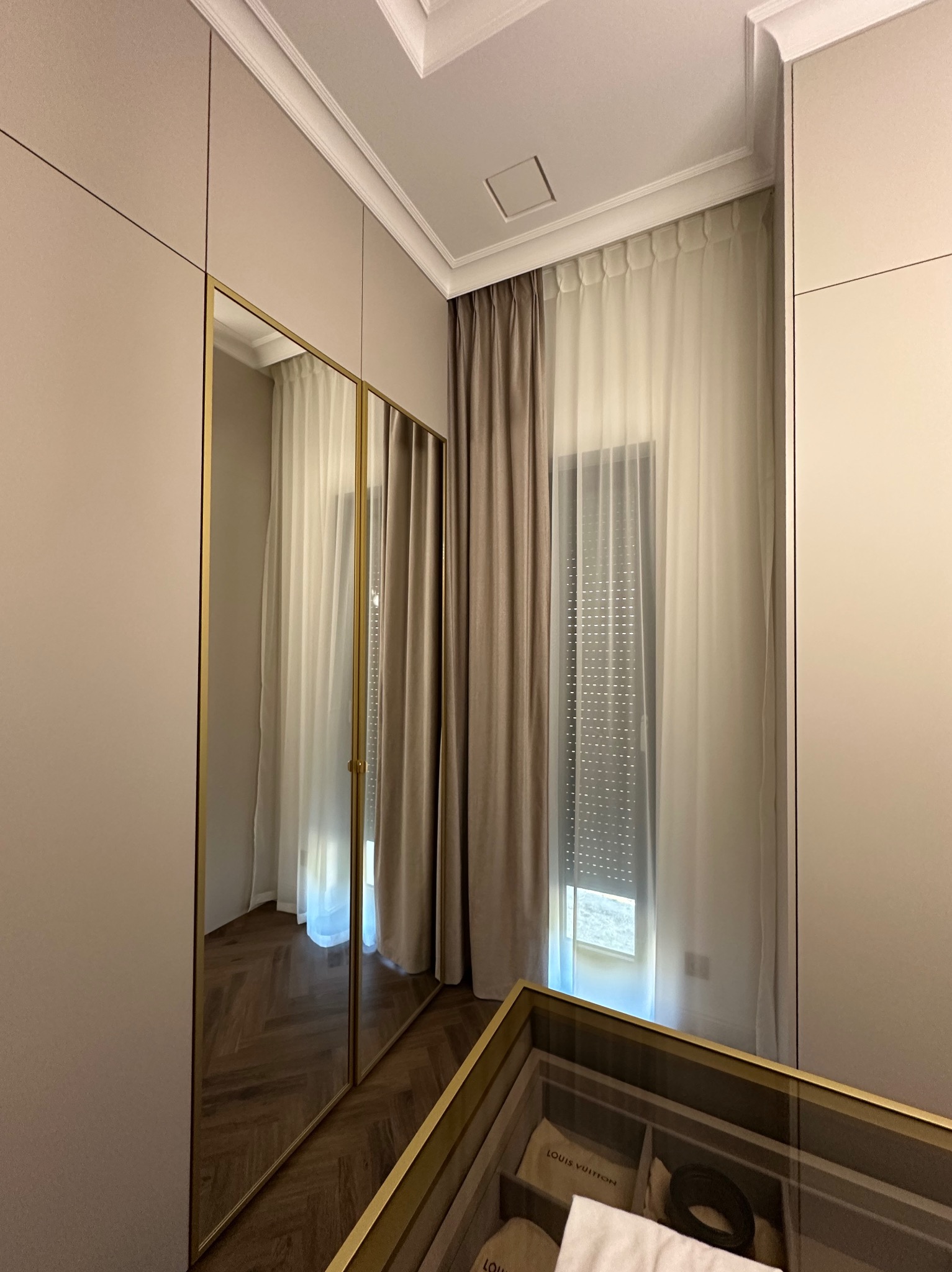 Eleganckie, beżowe zasłony w oknie z roletami wewnętrznymi, widoczne w lustrzanym odbiciu szafy w Inowrocławiu. Subtelne światło, minimalistyczny design.