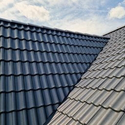 Star sp. z o.o. - Czarny dach z dachówki ceramicznej, widziany z góry, na tle błękitnego nieba w Kiełczowie. Widoczny fragment kalenicy.