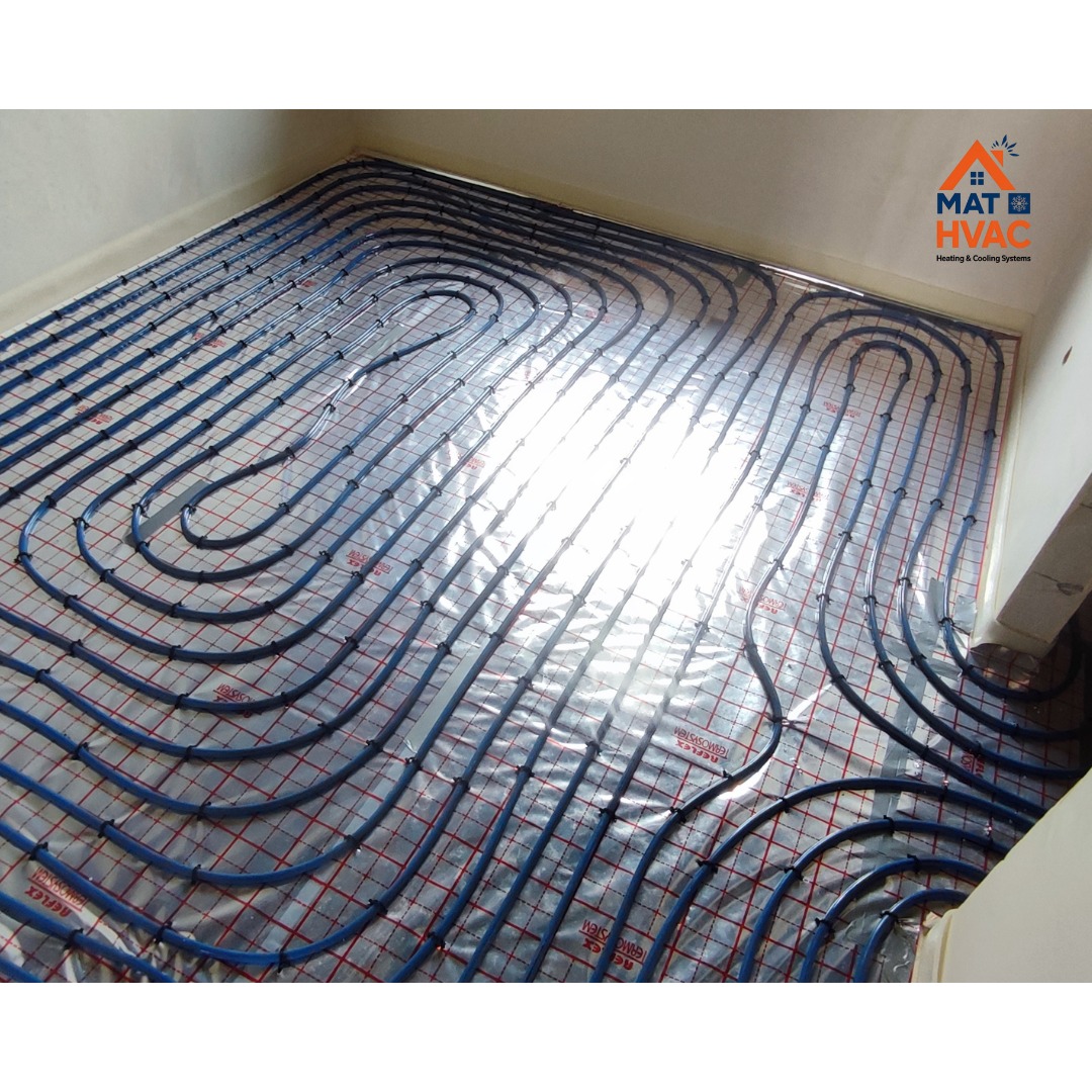 Błękitne rury ogrzewania podłogowego ułożone na folii z czerwoną siatką, widok z góry, jasne światło odbija się od folii. Instalacja przed wylaniem posadzki.