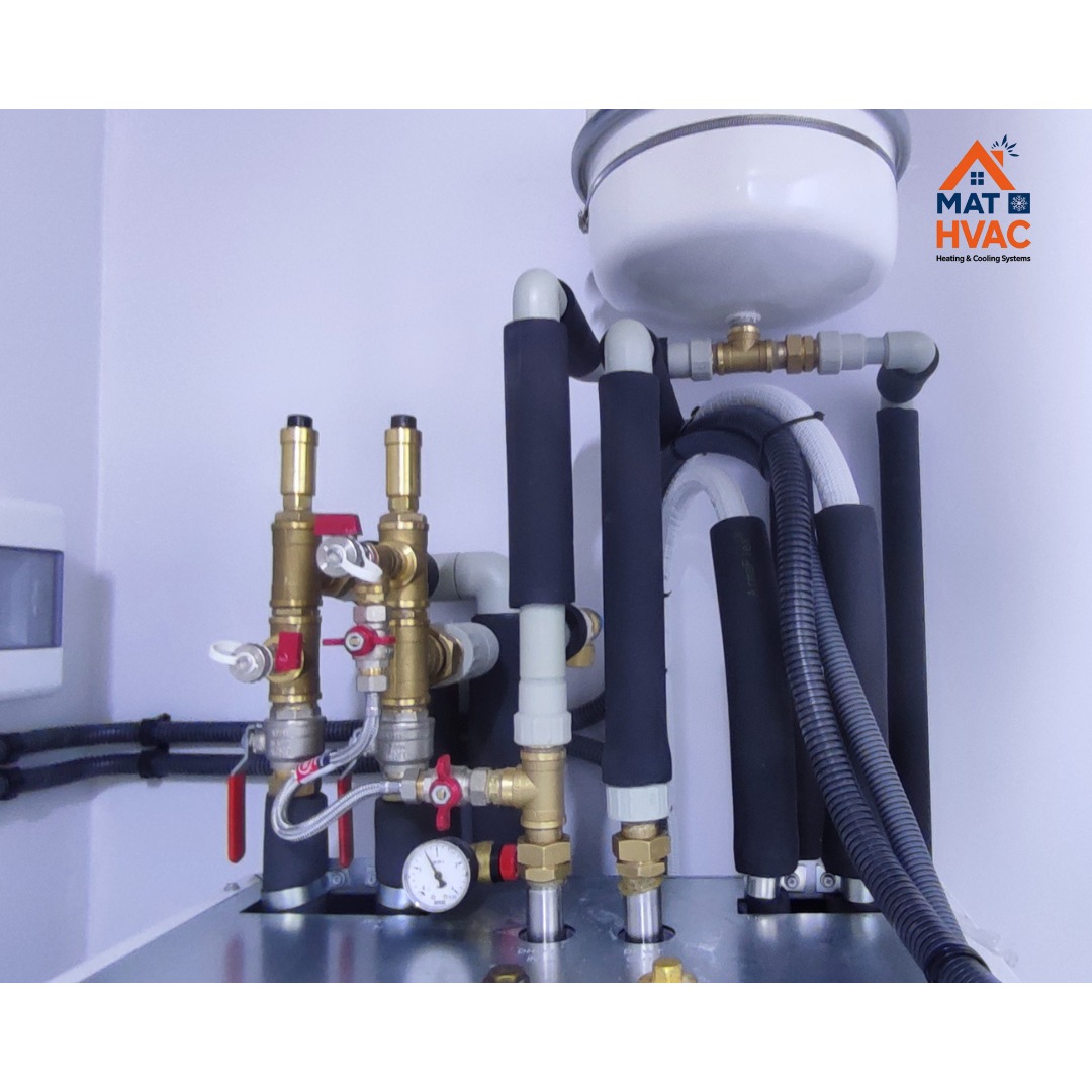 Złożony system rur, zaworów i izolacji termicznej, prawdopodobnie element instalacji grzewczej lub hydraulicznej. Widoczny manometr i zbiornik wyrównawczy.