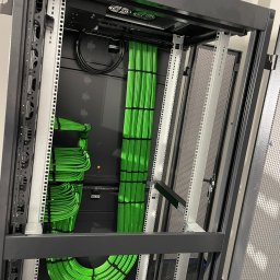 Dariusz Drzewi - Szafa serwerowa z uporządkowanymi, zielonymi kablami. Profesjonalny montaż przewodów w serwerowni. Estetyczne i funkcjonalne rozwiązanie.