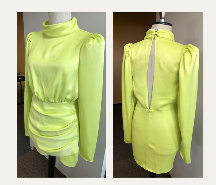 Neonowo-zielona, satynowa sukienka mini z długim rękawem i golfem, prezentowana z przodu i z tyłu na manekinie. Widoczny rozporek na plecach i marszczenia na spódnicy.