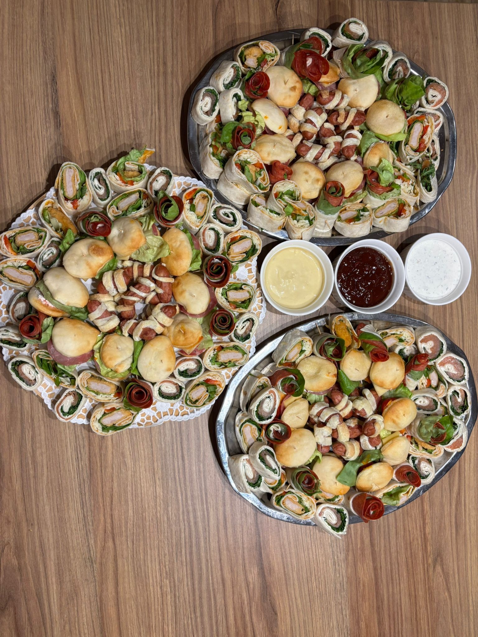 Elegancko ułożone na paterach przekąski: roladki z tortilli, mini kanapki i koreczki. Dodatkowo trzy miseczki z sosami. Idealne na catering firmowy lub imprezę okolicznościową.