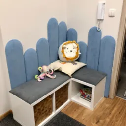 Kącik zabaw z niską zabudową, miękkimi siedziskami i pluszakami w gabinecie. Pastelowe kolory, przyjazna atmosfera, idealne miejsce dla dzieci.