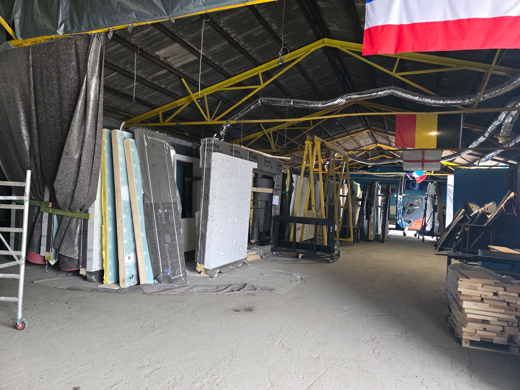 Magazyn elementów konstrukcyjnych w Strzelcach Krajeńskich. Widoczne płyty izolacyjne, rusztowanie i elementy konstrukcji stalowej pod dachem.