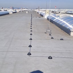 VSpark Volodymyr Semenikhin - Instalacja odgromowa na dachu budynku. Widoczne elementy mocujące przewody i zwody pionowe. W tle świetliki dachowe i shadow autora zdjęcia.