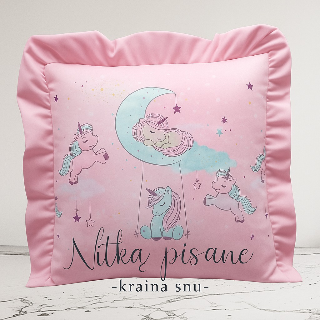 Różowa poduszka dekoracyjna z falbanką i nadrukiem jednorożców oraz napisem 'Nitka pisane -kraina snu-', leżąca na białym tle.