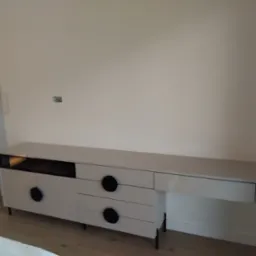 Biała komoda RTV na wymiar z czarnymi, okrągłymi uchwytami i czarnymi n&oacute;żkami, wykonana na zam&oacute;wienie w Radomsku. Nowoczesny design, minimalistyczny styl.