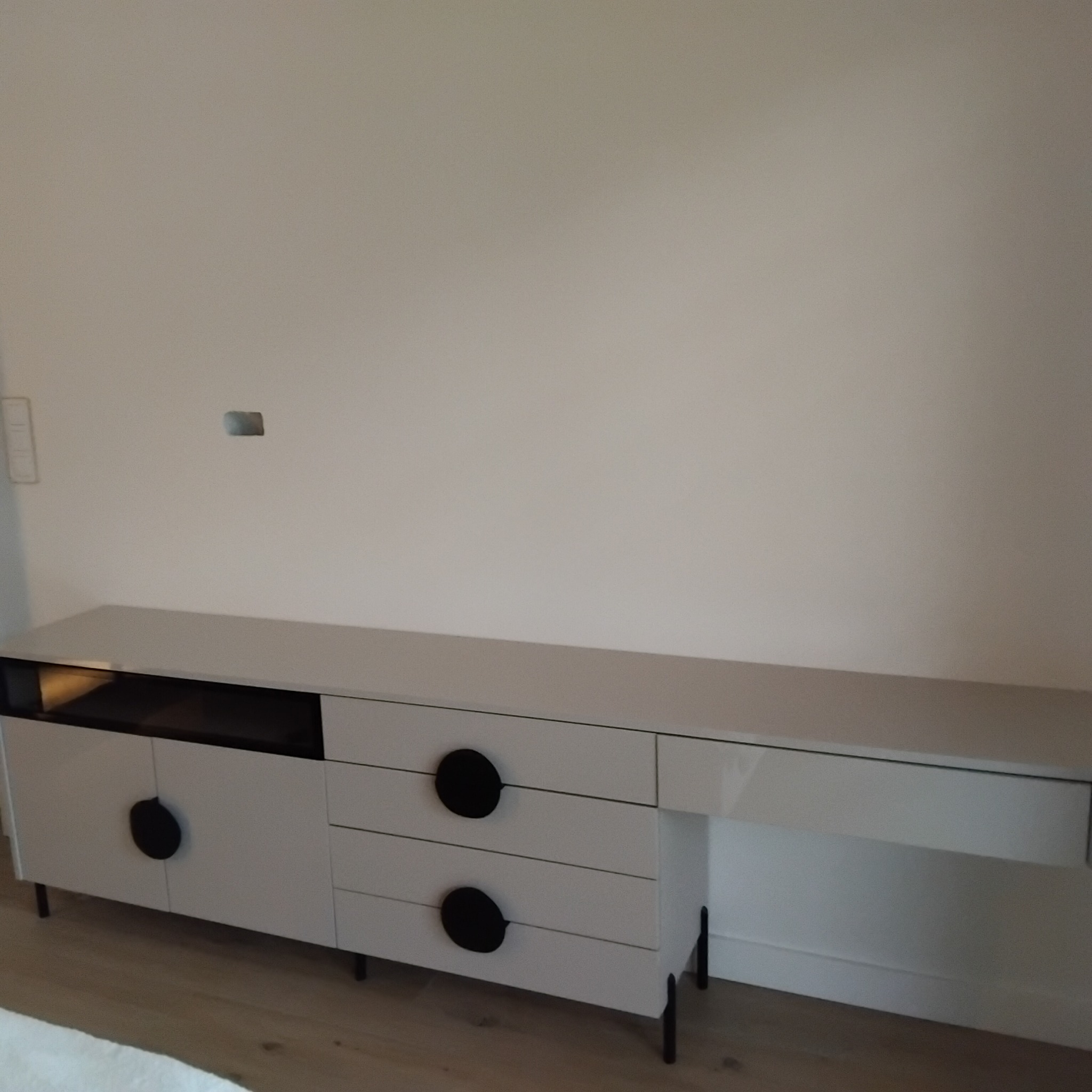 Biała komoda RTV na wymiar z czarnymi, okrągłymi uchwytami i czarnymi nóżkami, wykonana na zamówienie w Radomsku. Nowoczesny design, minimalistyczny styl.