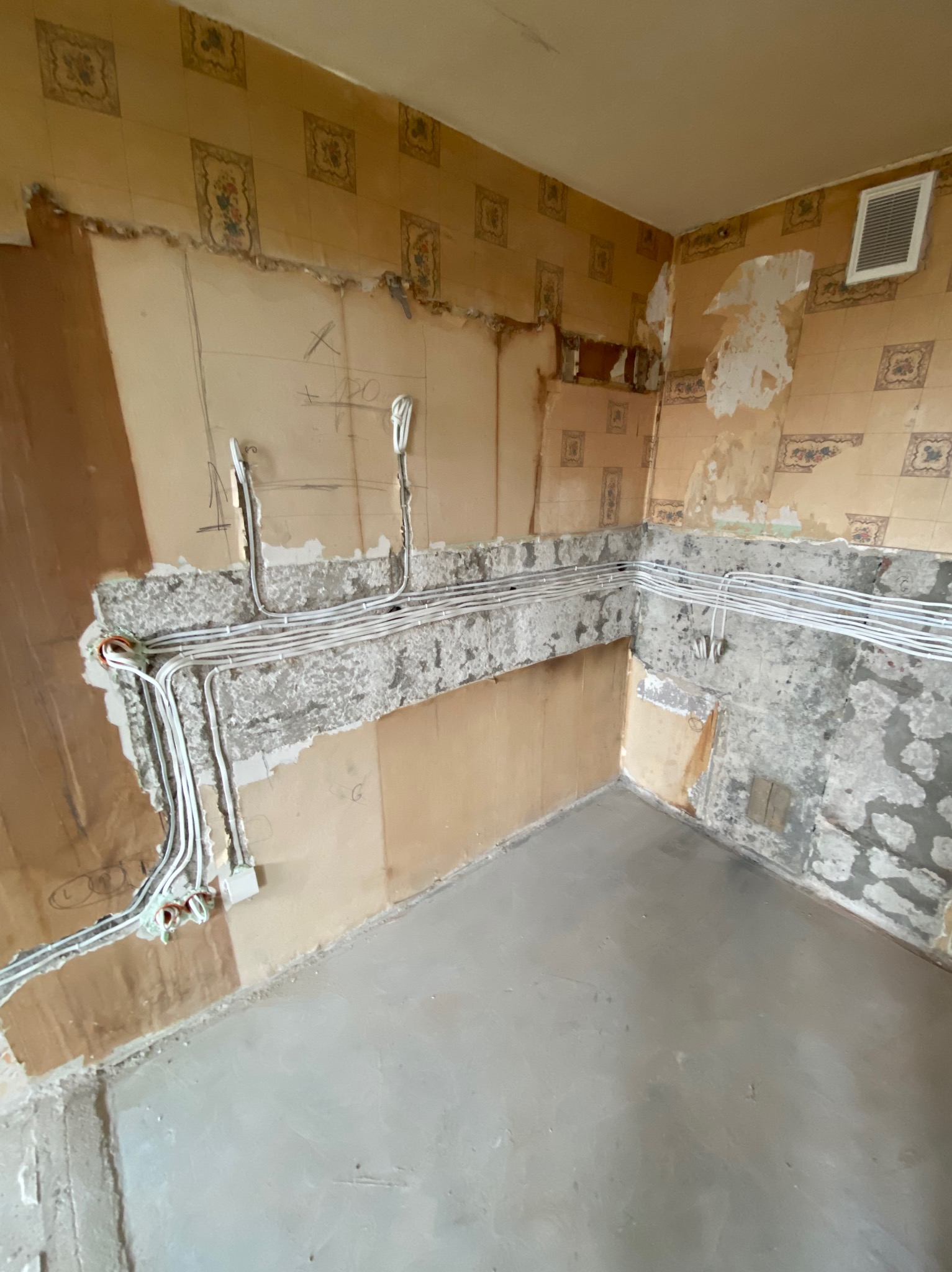 Remont kuchni: ułożone przewody elektryczne w bruzdach ściany, przygotowane do dalszych prac wykończeniowych. Widoczne ślady po starych płytkach i tapetach.