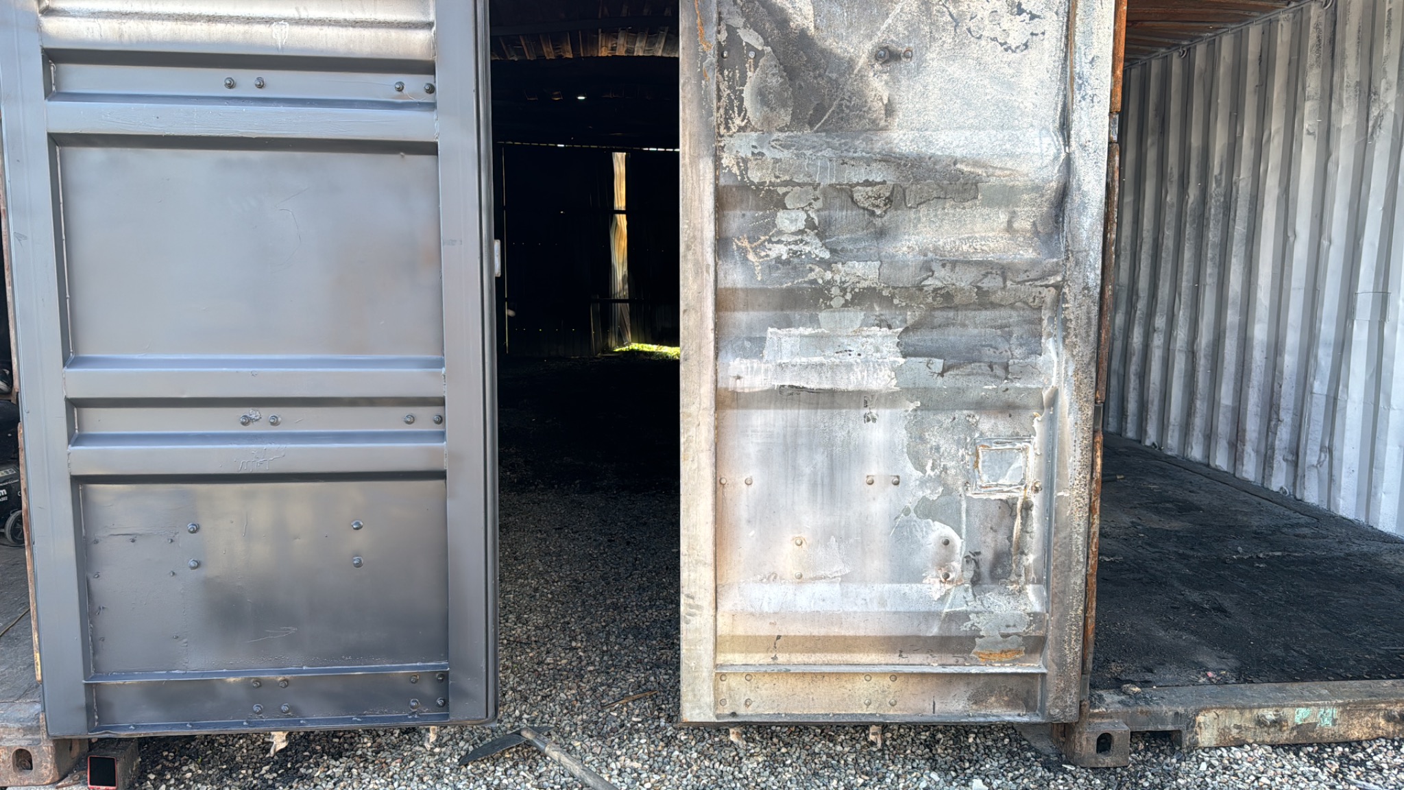 Otwarty kontener: jedna połowa drzwi świeżo pomalowana na szaro, druga z widocznymi śladami rdzy i uszkodzeń. Wnętrze kontenera częściowo widoczne.