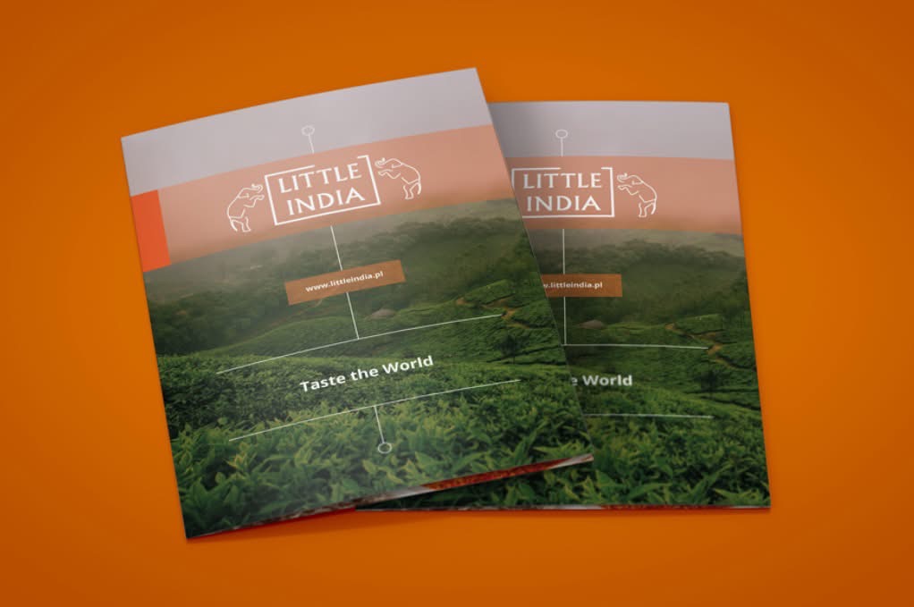 Dwa identyczne, matowe foldery reklamowe 'Little India' z motywem plantacji herbaty na okładce, leżące na pomarańczowym tle. Widoczna nazwa firmy i hasło 'Taste the World'.