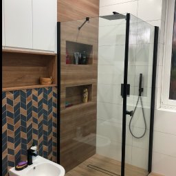MEDAN Usługi Remontowo-Wykończeniowe Daniel Mech - Nowoczesna łazienka z kabiną typu walk-in, drewnopodobne płytki, białe szafki i bidet. Uwagę przyciągają chevronowe płytki na ścianie.