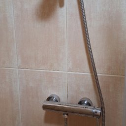 M-perfekt. Małgorzata Duda - Bateria prysznicowa z deszczownicą na beżowych płytkach. Chromowana armatura łazienkowa po czyszczeniu, widoczne detale wykończenia.