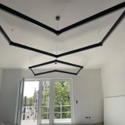 Nowoczesne oświetlenie sufitowe z czarnymi, geometrycznymi oprawami w jasnym pokoju z balkonem, widok z dołu. Minimalistyczny design.