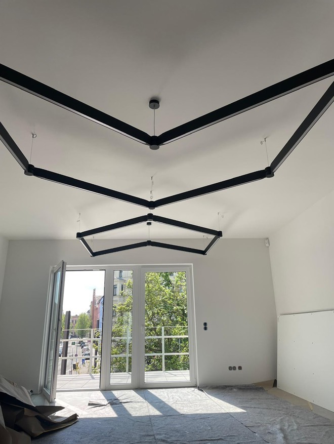 Nowoczesne oświetlenie sufitowe z czarnymi, geometrycznymi oprawami w jasnym pokoju z balkonem, widok z dołu. Minimalistyczny design.