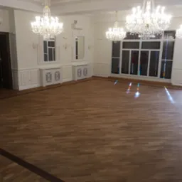 Sala balowa z parkietem w jodełkę, kryształowe żyrandole, okna ze szkła witrażowego i dekoracyjne grzejniki pod oknami. Parkiet z bordiurą.