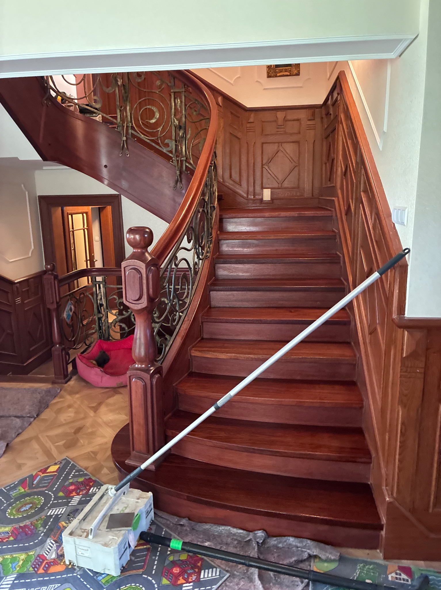 Renowacja drewnianych schodów z ozdobną balustradą. Widoczne narzędzia i elementy wykończenia. Schody po renowacji w odcieniach brązu.
