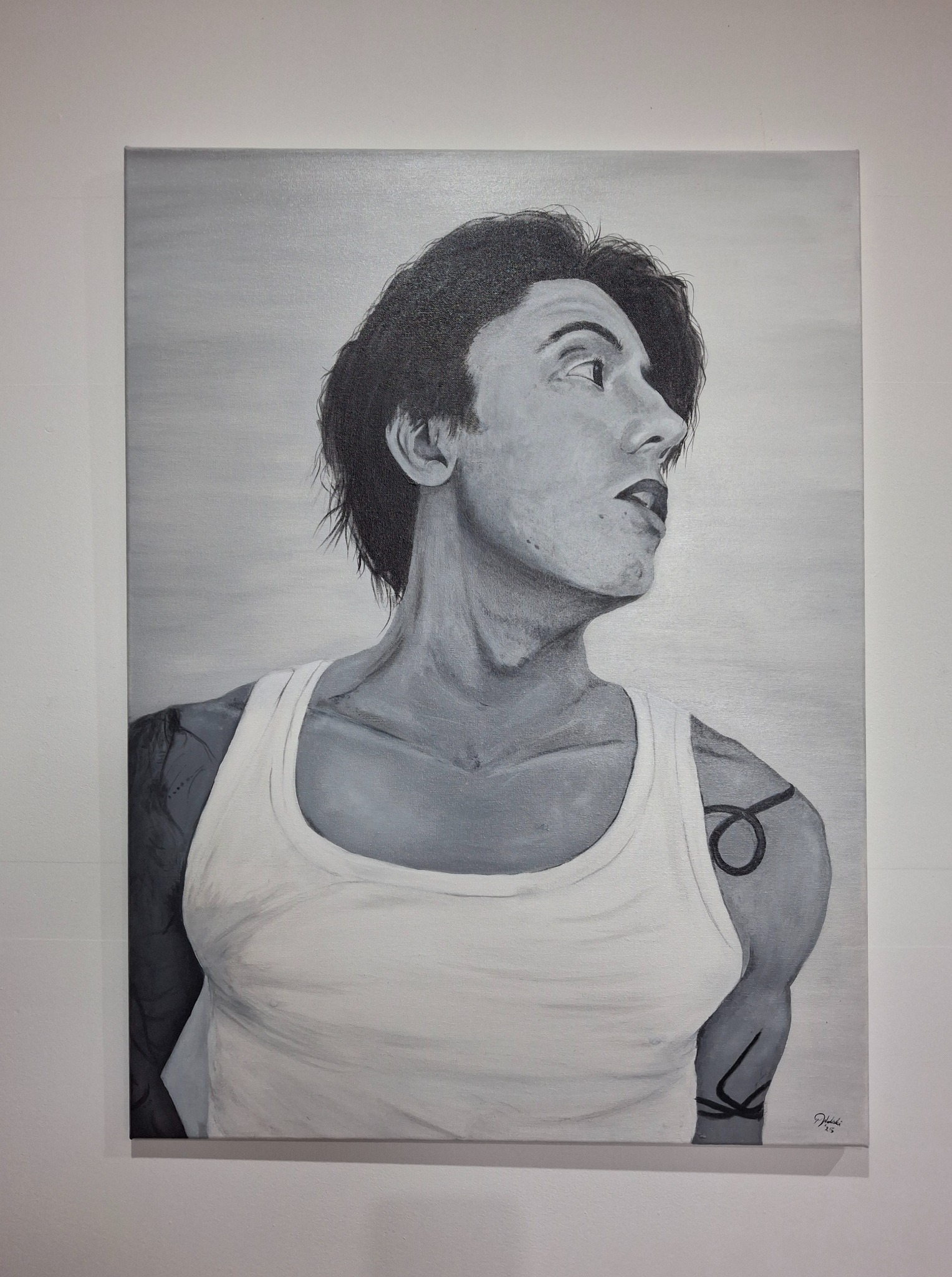 Czarno-biały portret mężczyzny z tatuażami, namalowany na płótnie. Widoczny z profilu, ubrany w biały podkoszulek, z widocznymi detalami tatuaży na ramionach.