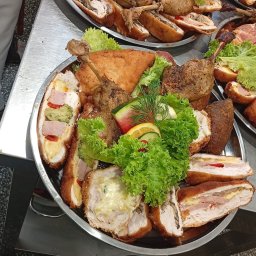 Restauracja Angello Joanna Smołka - Srebrna patera z pieczonymi udkami, roladkami z nadzieniem i świeżą sałatą, dekorowana cytrusami i ogórkiem.