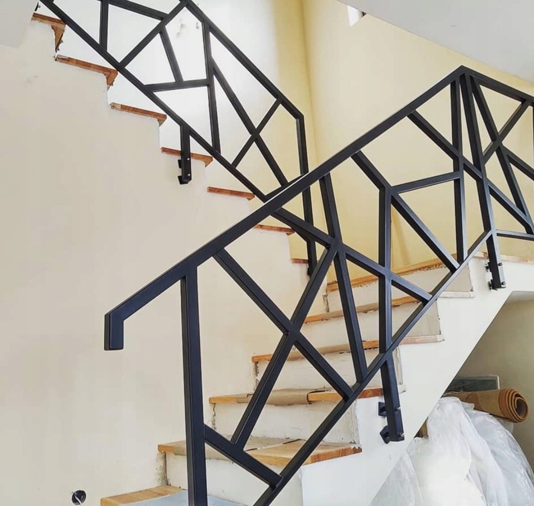 Nowoczesna, geometryczna balustrada schodowa w Łodzi. Czarna, metalowa konstrukcja z wyraźnymi liniami i kątami, zamontowana na białych schodach w jasnym wnętrzu.