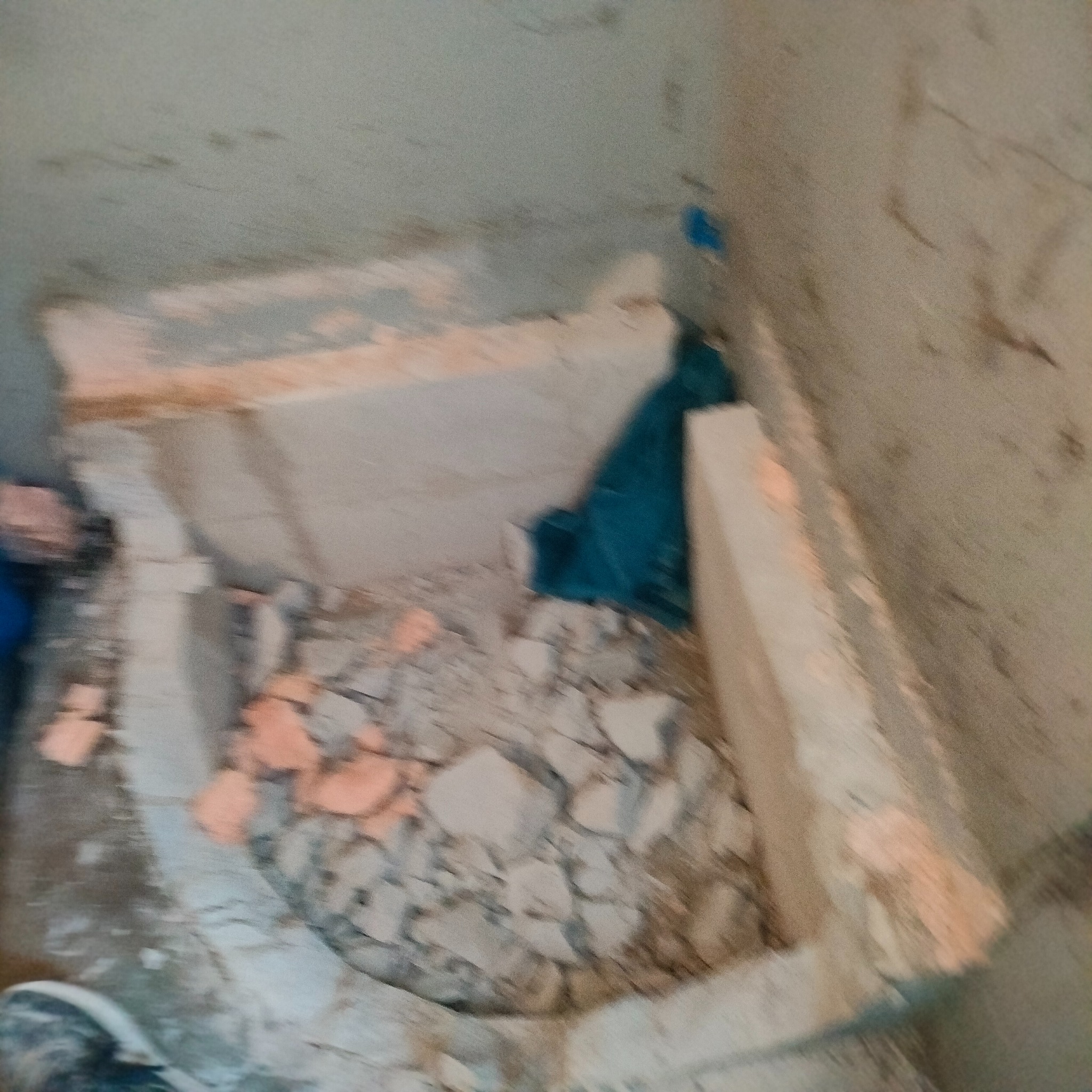 Kąt ujęcia na gruz i resztki materiałów budowlanych w rogu pomieszczenia, prawdopodobnie podczas demontażu elementów w trakcie remontu.