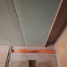 Szymon maciaszek - Montaż płyt gipsowo-kartonowych na suficie z widoczną izolacją w szczelinie. Detal wykończenia wnętrza w trakcie prac budowlanych.