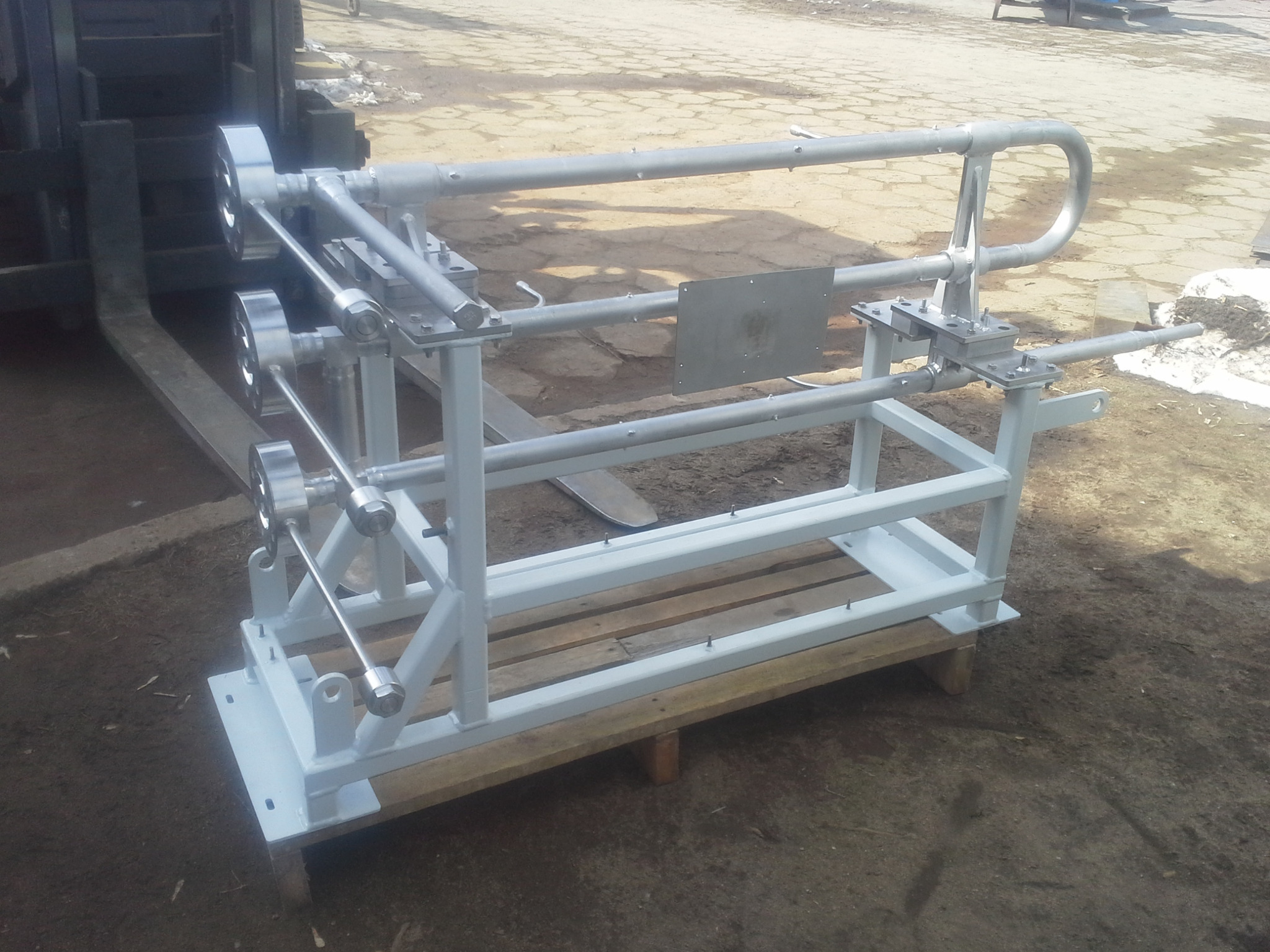 Metalowa konstrukcja spawana, pomalowana na biało, umieszczona na palecie, widoczna na zewnątrz w pochmurny dzień. Elementy konstrukcyjne z rur i blach.