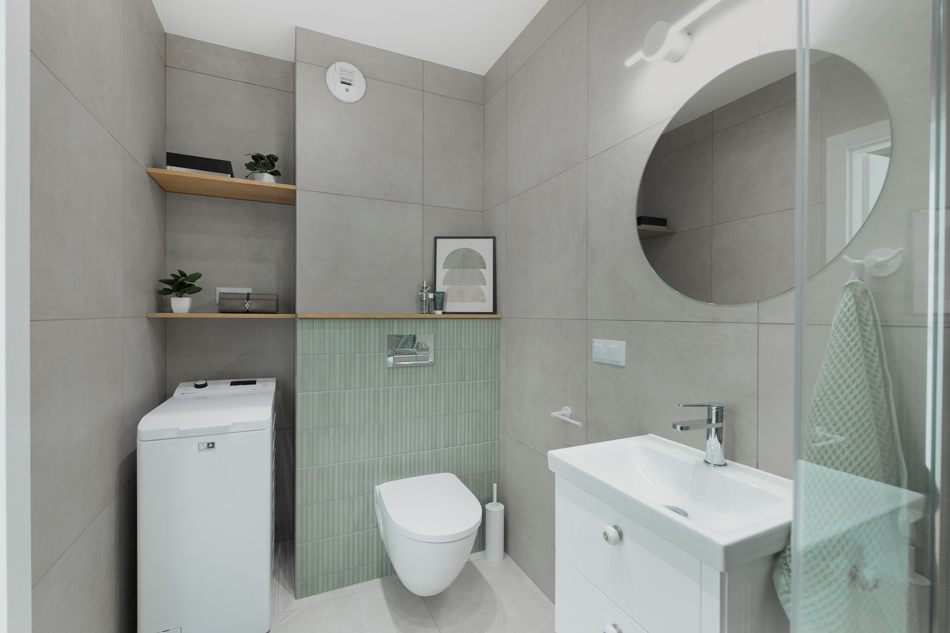 Nowoczesna łazienka w szarościach z akcentem pionowych, zielonych płytek. Umywalka z szafką, okrągłe lustro, pralka i drewniane półki.