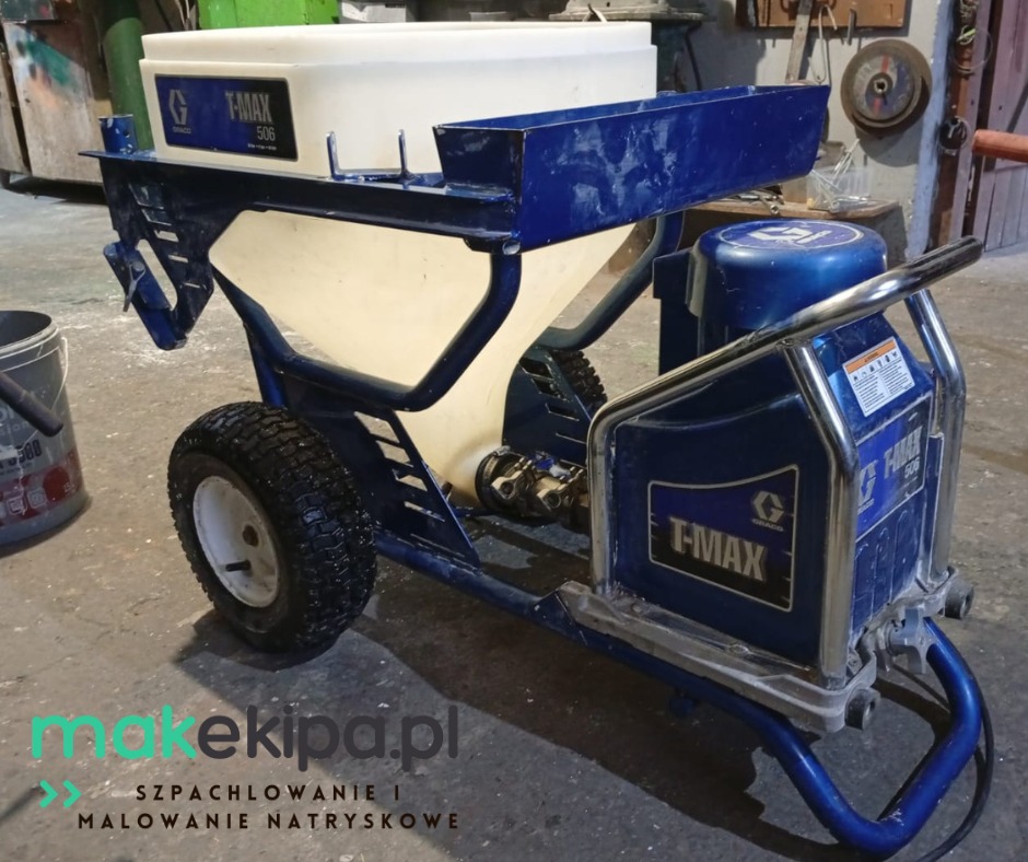 Profesjonalny agregat malarski Graco T-Max 506 na kółkach, z białym zbiornikiem i niebieską ramą, gotowy do natryskowego nakładania gładzi lub farb.