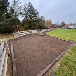 Green Tech - Przygotowany teren pod trawnik z rolki, obrzeża i ogrodzenie widoczne w Rucianem-Nidzie. Świeżo nawieziona ziemia i częściowo ułożone obrzeża.