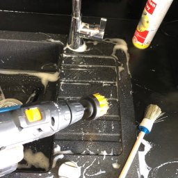 Twój Porządek - Czyszczenie zlewu szczotką na wiertarce i szczotką ręczną, piana czyszcząca, chromowana bateria. Czarny zlew z tworzywa sztucznego, czyszczenie mechaniczne.