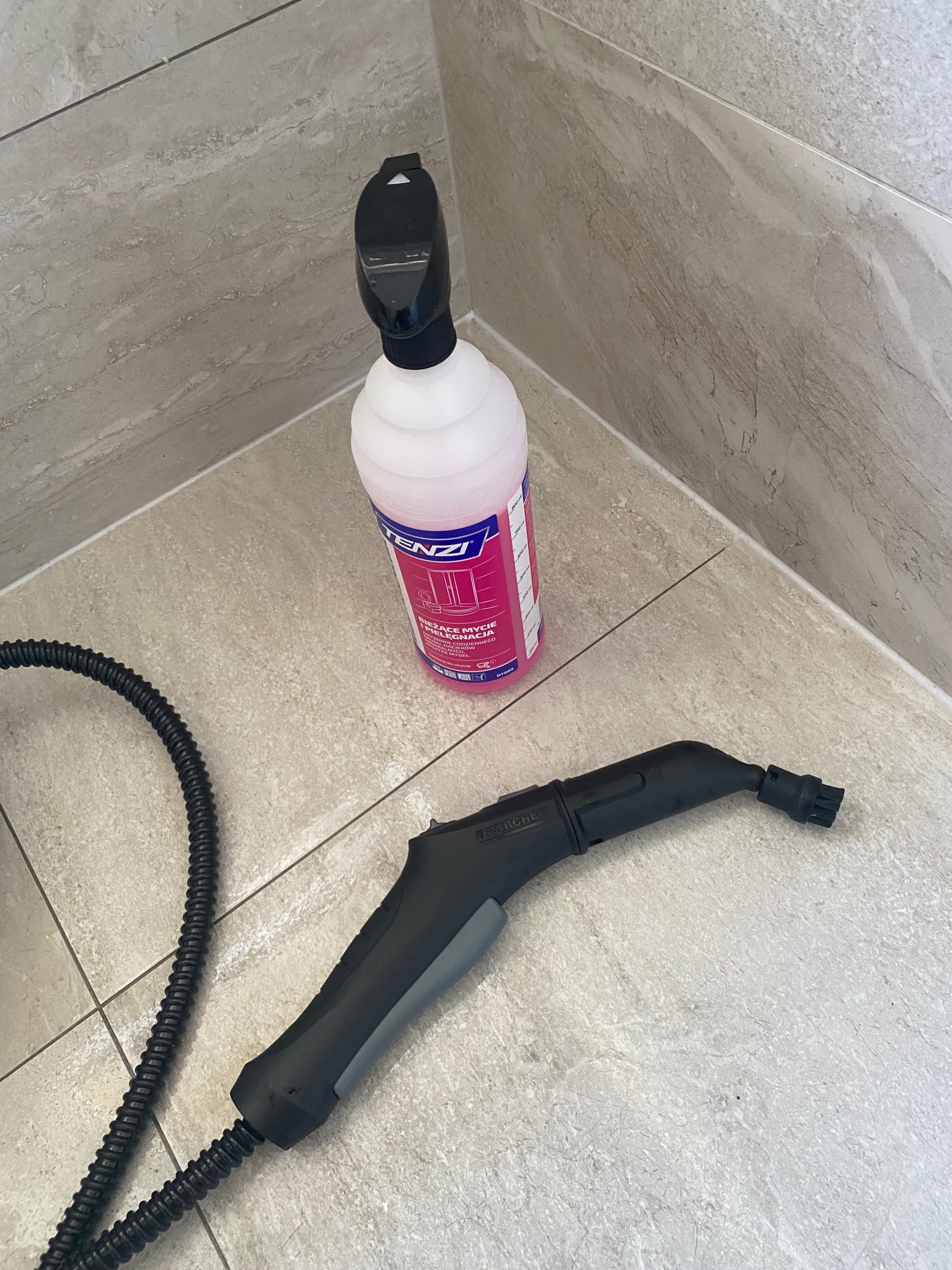 Płyn do mycia i parownica Karcher na jasnych płytkach podłogowych. Widoczne detale dyszy parowej i węża. Gotowość do sprzątania.