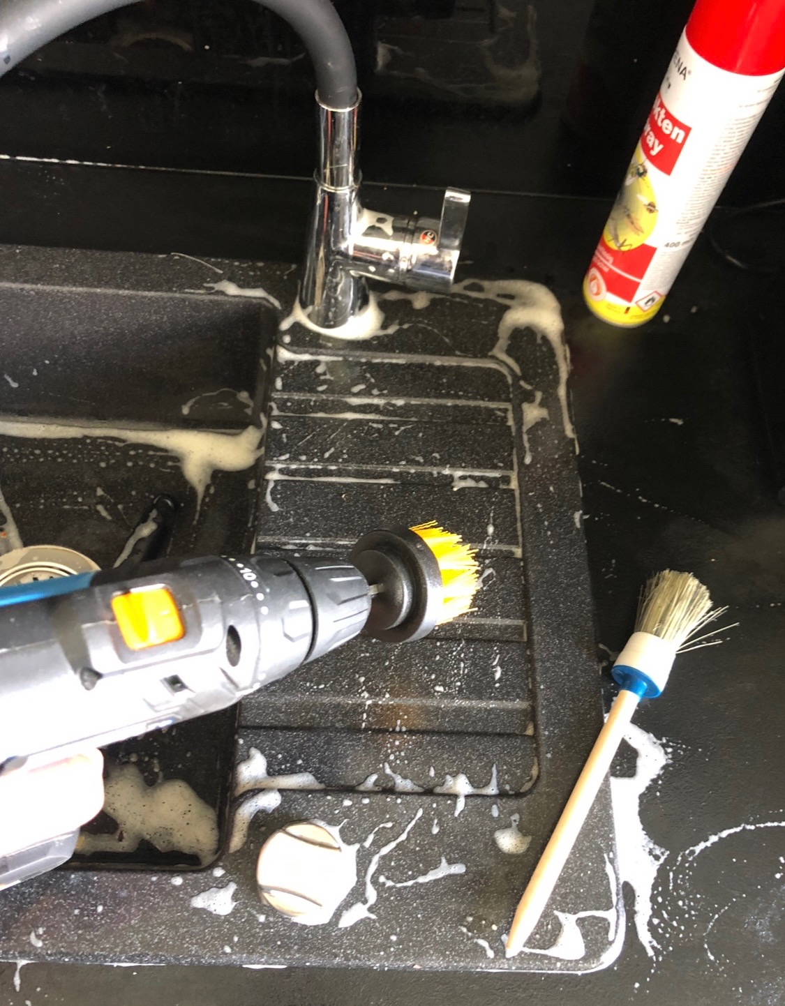 Czyszczenie zlewu szczotką na wiertarce i szczotką ręczną, piana czyszcząca, chromowana bateria. Czarny zlew z tworzywa sztucznego, czyszczenie mechaniczne.