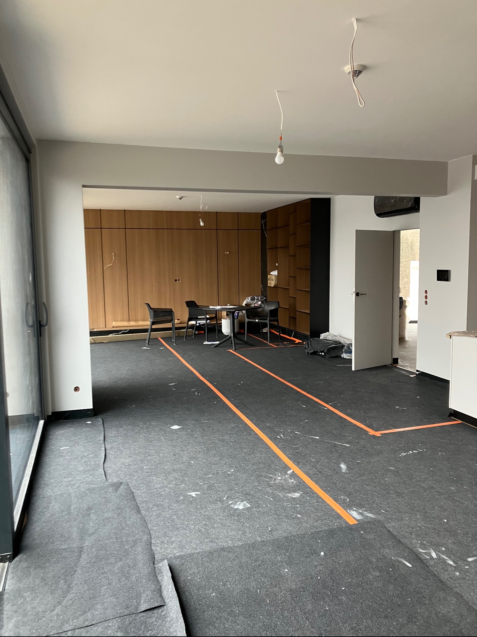 Przygotowanie do prac wykończeniowych: zabezpieczona podłoga folią, wyznaczone strefy pomarańczową taśmą w przestronnym wnętrzu z drewnianą zabudową.