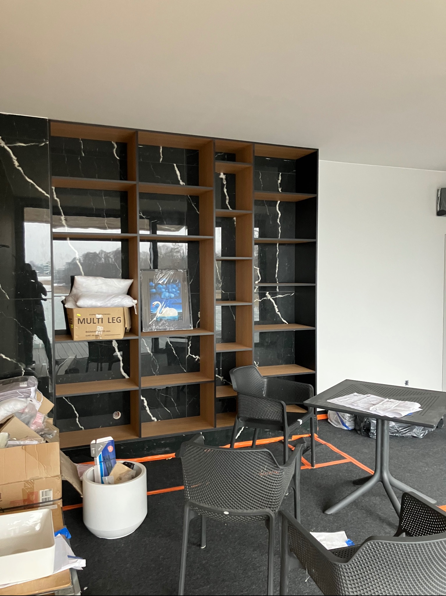 Wykończone regały z czarnym marmurem w Lubawie, z widocznymi półkami i elementami dekoracyjnymi. Nowoczesny design, widok na wnętrze w trakcie aranżacji.