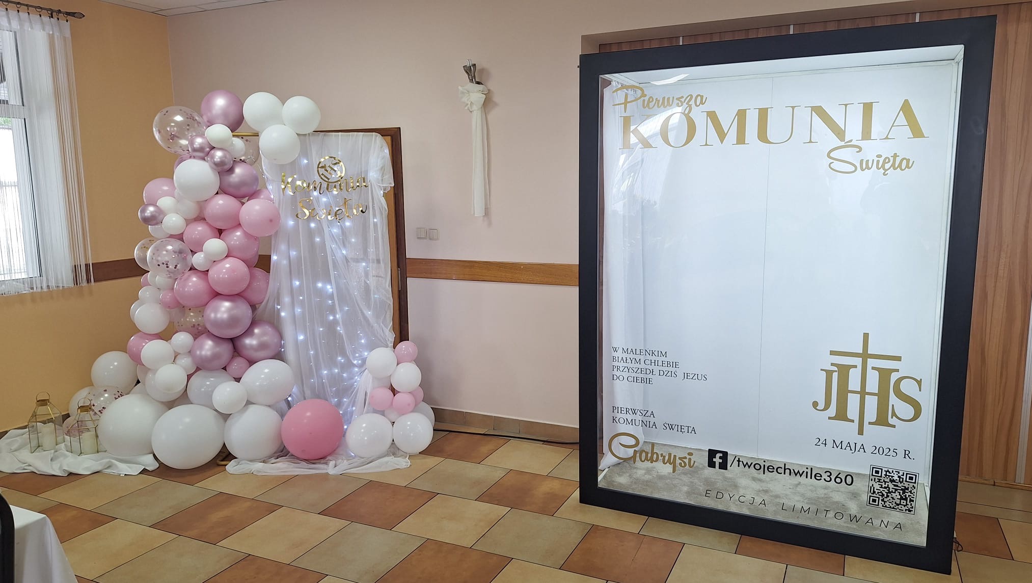 Dekoracja komunijna z balonów w odcieniach różu i bieli, oraz podświetlana ścianka z napisem 'Pierwsza Komunia Święta' i datą 24 maja 2025.