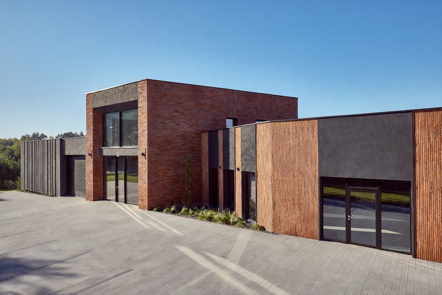 Nowoczesny budynek z elewacją z cegły klinkierowej i drewnianych paneli, z dużymi przeszkleniami i minimalistycznym otoczeniem. Widok z zewnątrz, w słoneczny dzień.