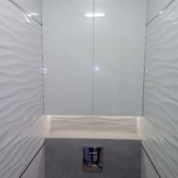 DWÓCH OD MEBLI Artur Sikorzyński - Nowoczesna, biała szafka wnękowa z połyskiem, zamontowana nad toaletą. Wzór płytek imituje fale. Chromowany przycisk spłuczki. Minimalistyczny design.