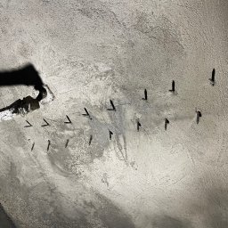 UBS - Świeżo wylany beton z wystającymi prętami zbrojeniowymi, widoczne ślady po szalunku i cień węża do betonu. Surowy stan w trakcie prac budowlanych.