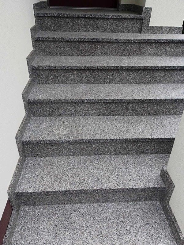 Granitowe schody wewnętrzne z szarego kamienia, widok z dołu. Minimalistyczny design, gładka powierzchnia stopni, nowoczesne wykończenie.