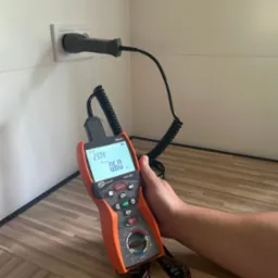 Pomiar napięcia w gniazdku elektrycznym za pomocą miernika Sonel MPI-507, z widocznym wskazaniem 237.4V i 0.60 omów na wyświetlaczu.