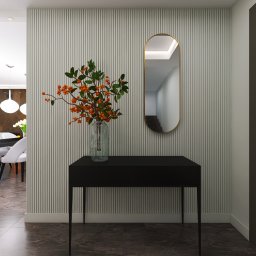 Renata Urban Projekty na 4 kąty - Hol z konsolą, lustrem i wazonem z gałązkami jarzębiny na tle ściany w pionowe pasy. W tle widoczny salon z jadalnią i białymi krzesłami. Nowoczesny styl.
