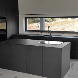 Matheo wood meble - Nowoczesna, minimalistyczna kuchnia w odcieniach szarości z wyspą, dużym oknem i marmurową podłogą. Widok na zewnątrz przez okno.